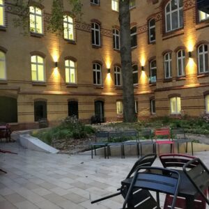 Schwarze Stühle in einem Innehof mit Beleuchtung. 